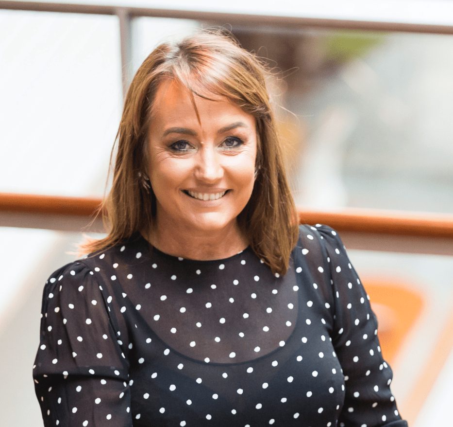 Dr Heidi Norman smiling at us in a blue top with white polka dots.