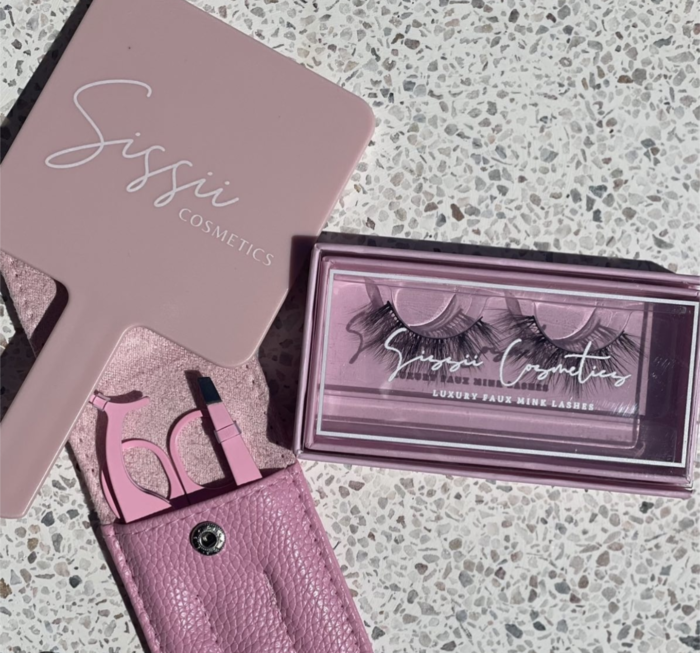 An image shot from above. Sissii Cosmetics products fake lashes and accompanying kit with tweezers and scissors are shown.