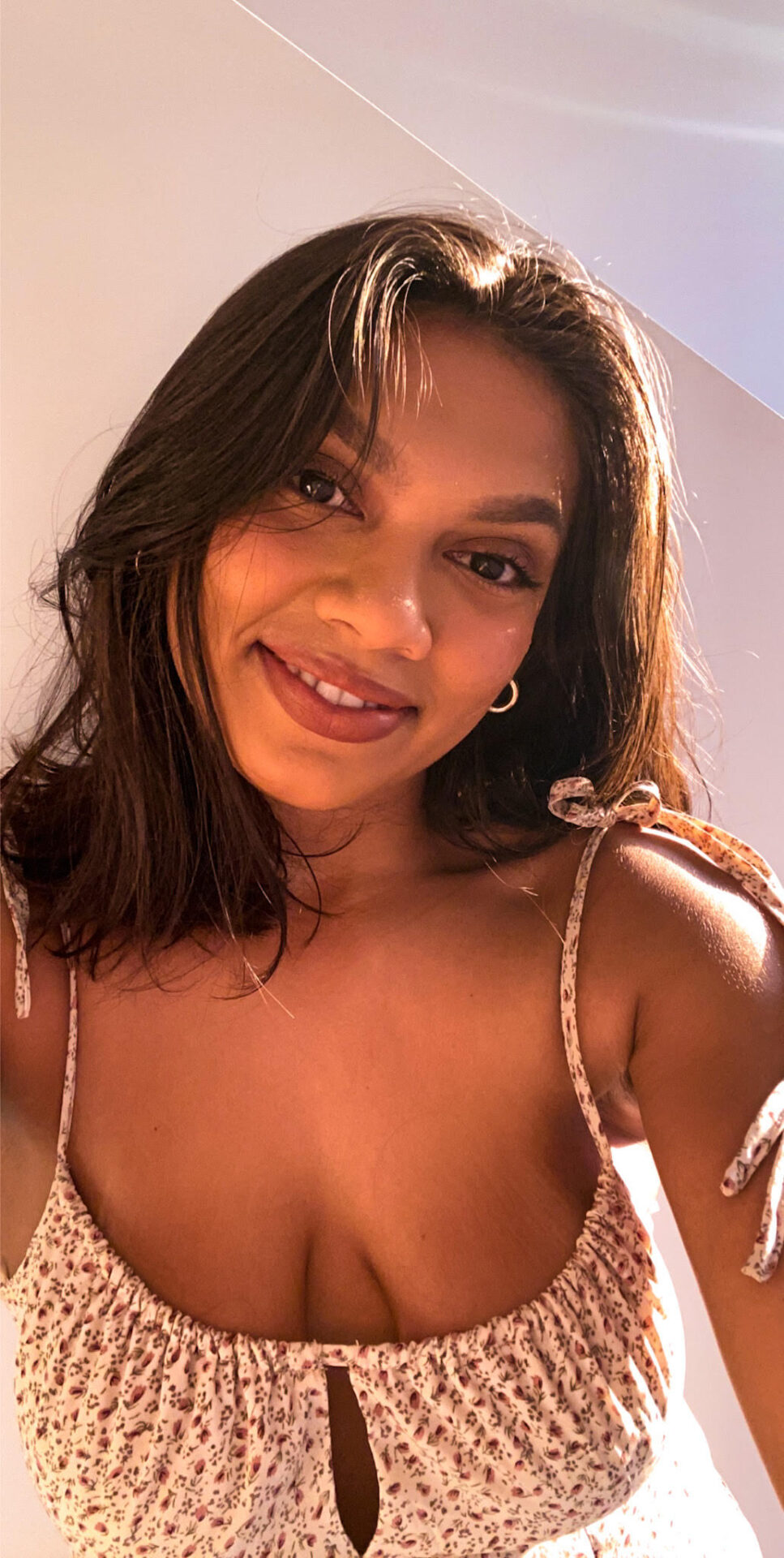 A person with long hair is smiling, and the lighting is a warm glow of the day.